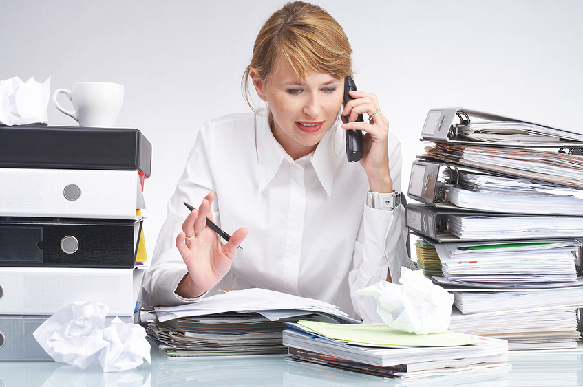 Woman talking on the phone surrounded by towers of binders.